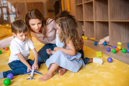 tutor-hugging-adorable-kids-on-carpet-in-kindergar-2022-11-02-01-23-38-utc 2